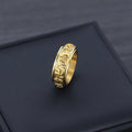 Single gold Taoist KaiGuang spinner ring on dark background showing engraved rune pattern
