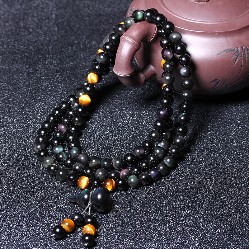  Taoist KaiGuang obsidian bracelet held in hand showing tiger eye gold grain and black bead detail