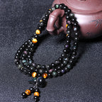  Taoist KaiGuang obsidian bracelet held in hand showing tiger eye gold grain and black bead detail