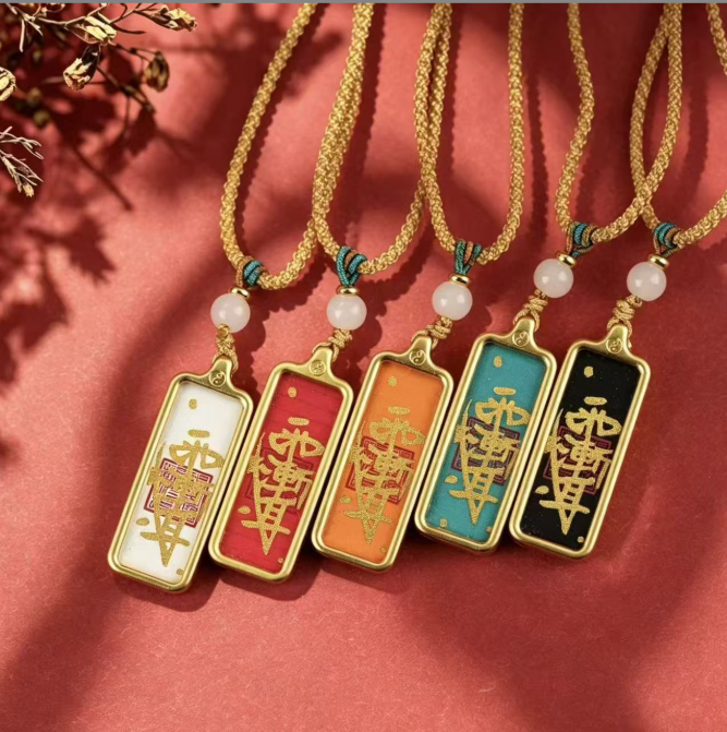 Five Taoist talisman pendants with white, red, orange, teal and black faces displayed side by side.