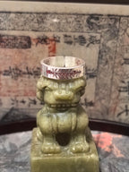 Macro shot of the Cinnabar-activated Five-Thunder Ring, positioned on a sacred guardian lion to double its protective and evil-banishing power.