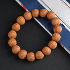 Natural wild walnut wealth bracelet full circle on dark background with book prop showing round uniform beads Taoist KaiGuang positive energy cleansing spiritual bracelet