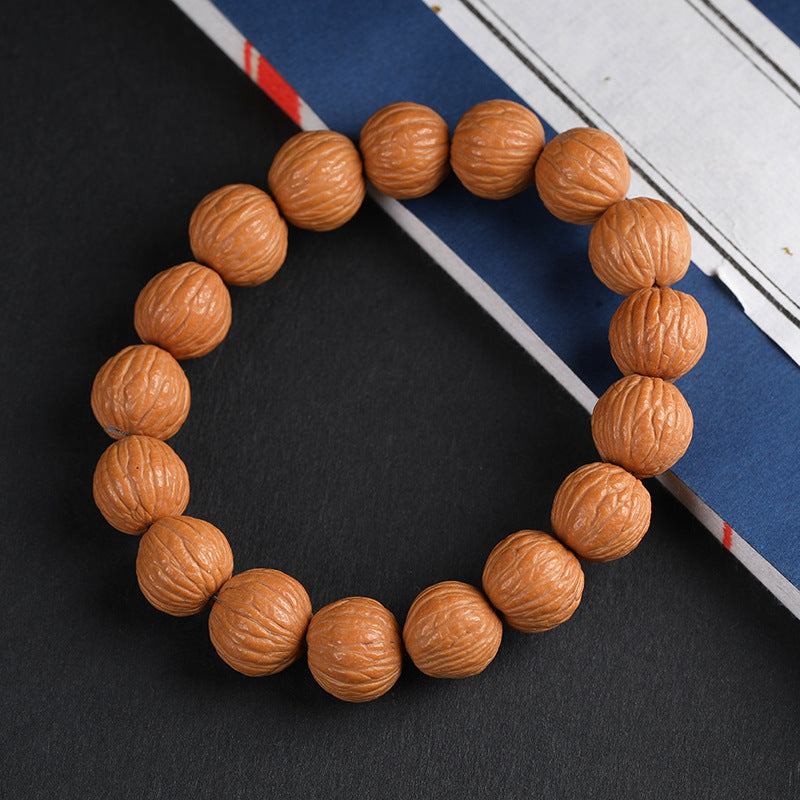 Natural wild walnut wealth bracelet full circle on dark background with book prop showing round uniform beads Taoist KaiGuang positive energy cleansing spiritual bracelet