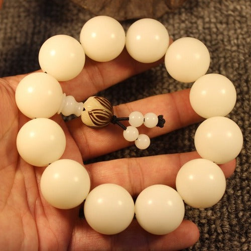 White bodhi root healing bracelet held in hand showing bead size and natural ivory white color