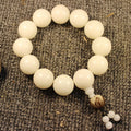 White bodhi root Taoist KaiGuang bracelet lying on linen showing large round beads and small tassel detail