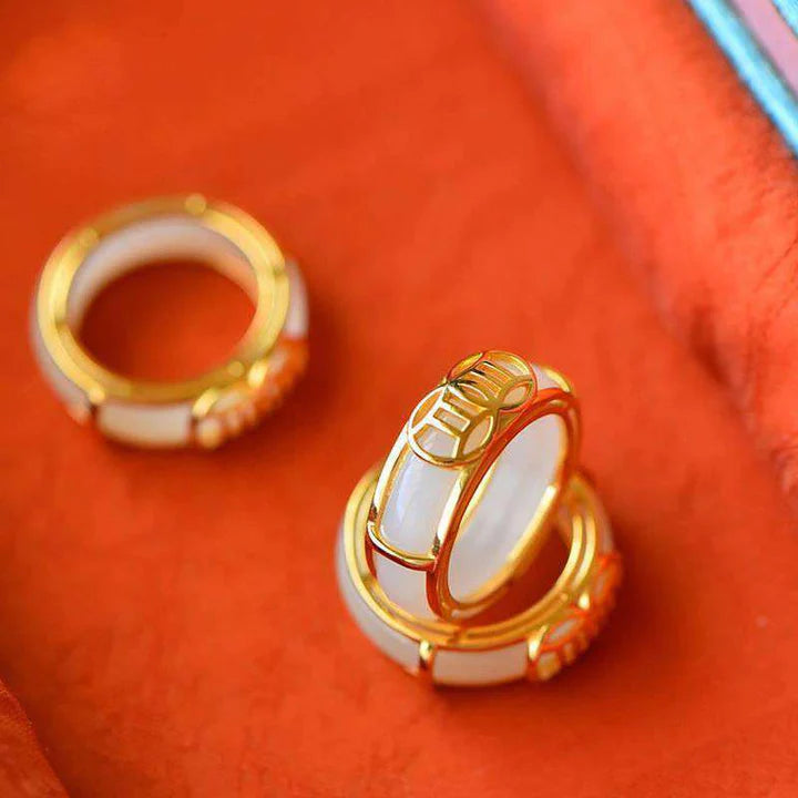 White jade Taoist KaiGuang ring top view on orange background showing inner band and contrasting gold edge