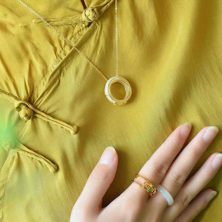  White jade luck fortune protection ring worn on finger against yellow green background showing fit and size