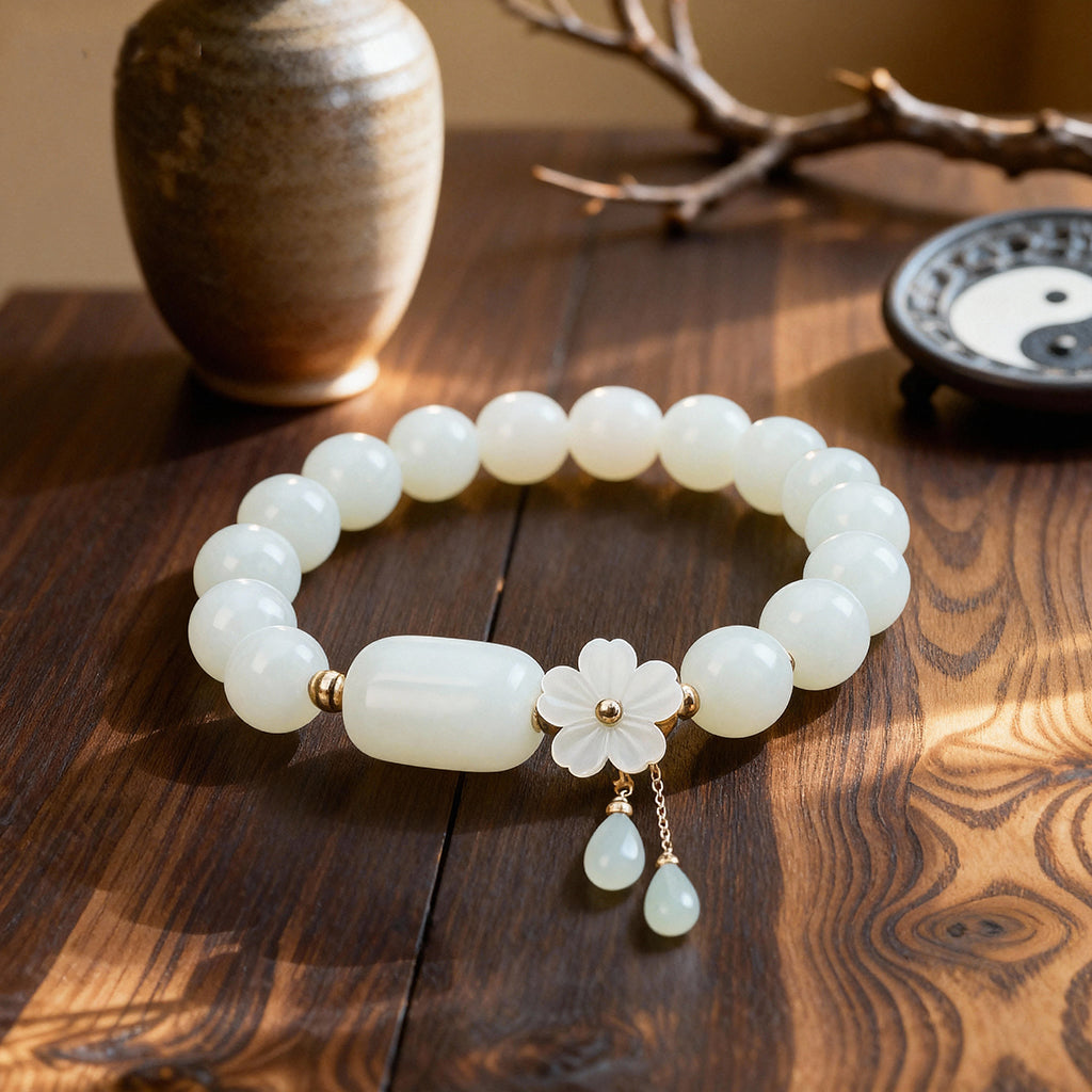 Natural white jade Taoist KaiGuang bracelet with white flower charm and double jade drop pendant against dark tree bark background