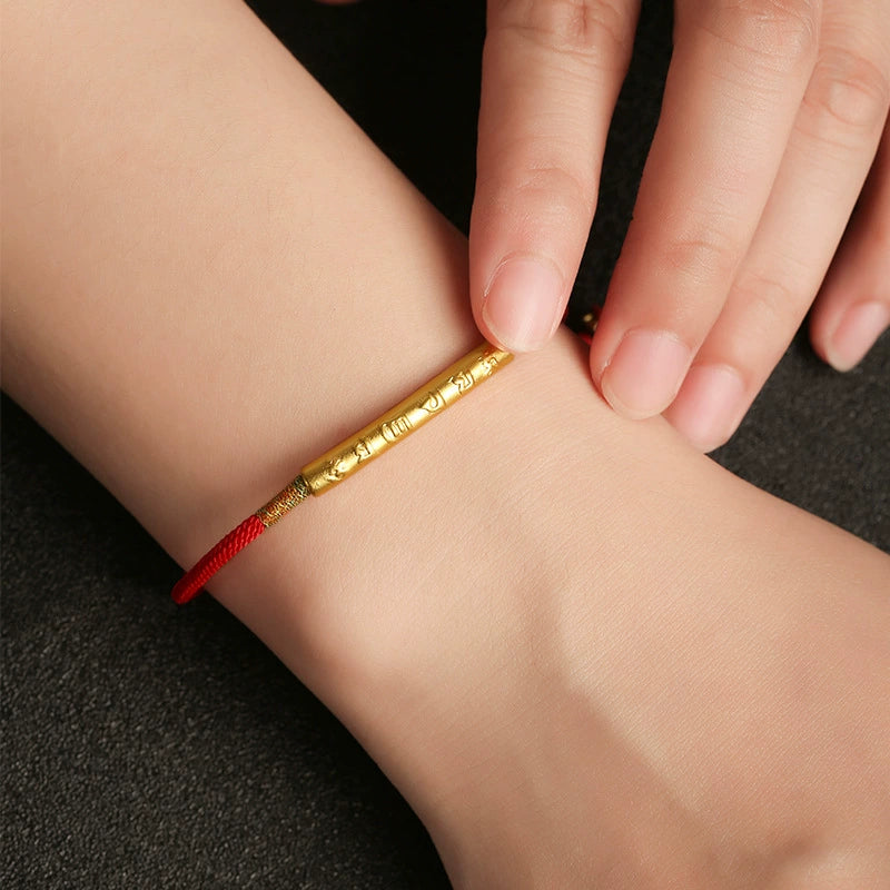 Woman wearing red rope KaiGuang protection bracelet with engraved gold mantra tube on wrist